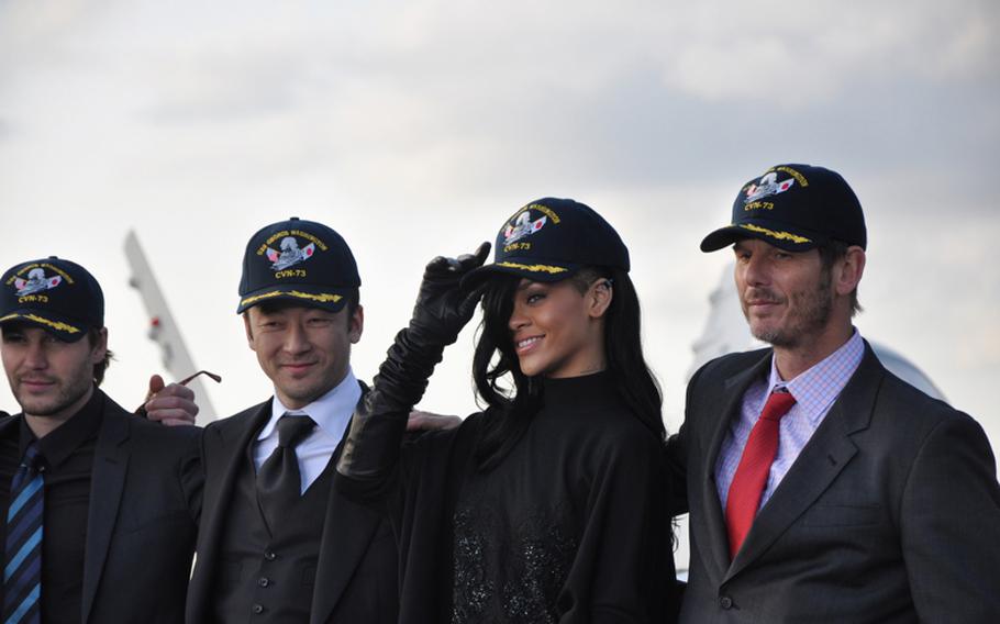 The cast and crew from the movie "Battleship" accept USS George Washington caps aboard the aircraft carrier following a press conference on the flight deck Monday. Pictured from left are actor Taylor Kitsch; Japanese actor Tadanobu Asano; pop singer Rihanna, who makes her acting debut in the film; and director Peter Berg.