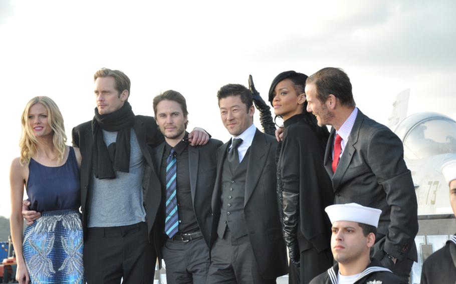 The cast and crew from the movie "Battleship" pose aboard the aircraft carrier USS George Washington following a press conference on the flight deck Monday. Pictured from left on stage are Brooklyn Decker, Alexander Skarsgard, Taylor Kitsch, Tadanobu Asano, Rihanna and director Peter Berg.