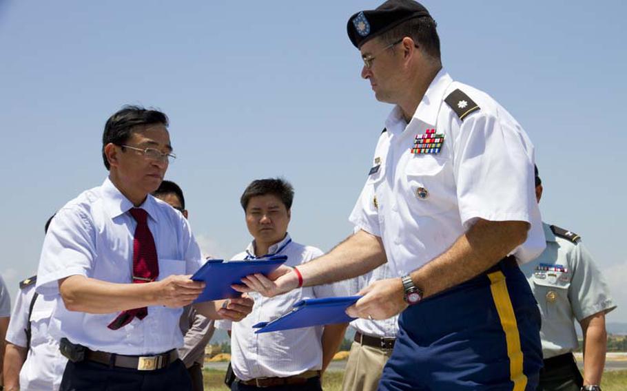 Army Lt. Col. Patrick Keane exchanges repatriation documents with Senior Col. Dao Xuan Kinh. the deputy director of the Vietnam Ministry of Defense&#39;s Office for Seeking Missing Persons, during a ceremony at Danang Airport on April 9. The ministry turned over remains believed to be a servicemember killed during the Vietnam War.