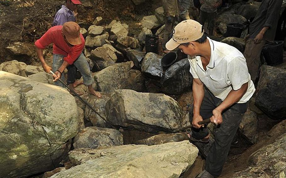 Local Vietnamese men assisting the Joint POW/MIA Accounting Command and the Vietnam Office for Seeking Missing Persons, (VNOSMP) use pry bars to remove large boulders from a stream bed in Binh Dinh Province, Vietnam March 14, 2012. The stream bed is being carefully excavated for any sign of osseous material or other evidence that can help identify a soldier missing from the Vietnam Conflict.  JPAC&#39;s mission is to conduct global search, recovery and laboratory operations to identify unaccounted-for Americans from past conflicts in order to support the Department of Defense&#39;s personnel accounting efforts.