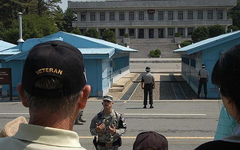 An escort briefs a group of U.S. Korean War veterans at the Joint Security Area of Korea's Demilitarized Zone on May 23, 2012. The group, accompanied by their families and South Korean schoolgirls, visited several sites in and around the DMZ.