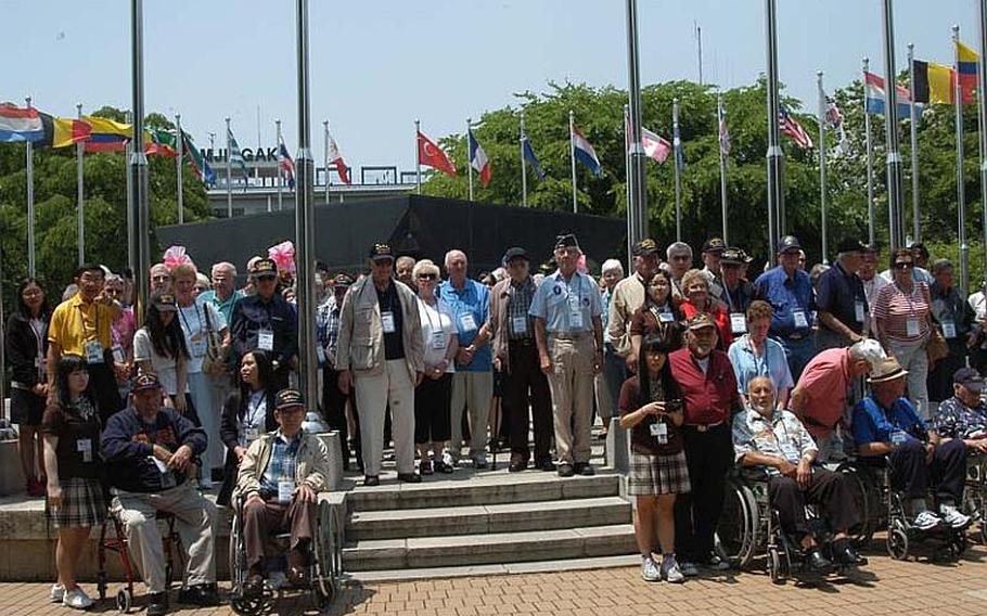 A group of U.S. Korean War veterans, accompanied by their families and South Korean schoolgirls, pose May 23, 2012, at a monument, located near the Demilitarized Zone, dedicated to American participation in the war.