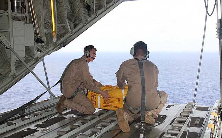 Lance Cpl. Eric Bruning, left, and Vinson Gallardo with Marine Aerial Refueler Transportation Squadron 152 drop a life raft containg food, water and other survival aids to two men aboard a skiff who were stranded 60 nautical miles northwest of Chuuk Island.
