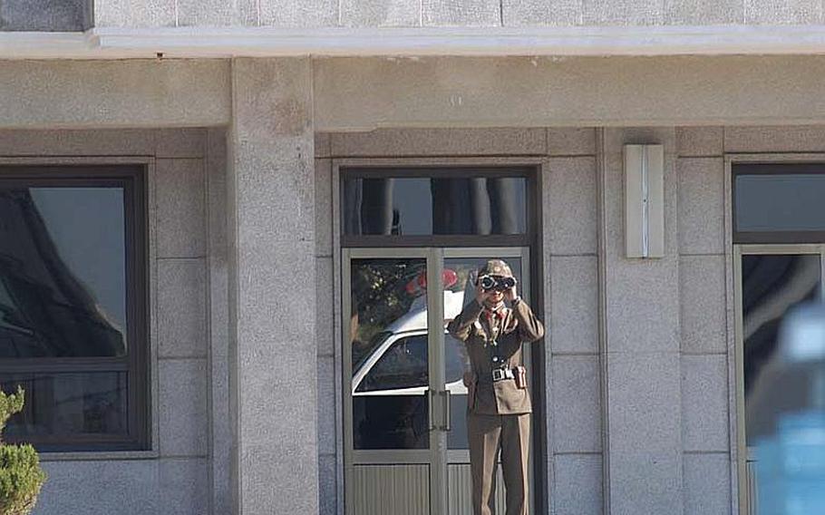 A North Korean soldier peers across the Joint Security Area of the Demilitarized Zone on Oct. 18, 2012, after a repatriation ceremony. Reflected in the window behind him is the ambulance that carried away the remains of a North soldier that were returned during the event.
