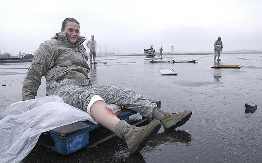 Senior Airman Amanda Kelly waits in the rain with a simulated broken tibia on Nov. 6, 2012, during a mock disaster exercise at Yokota Air Base, Japan.