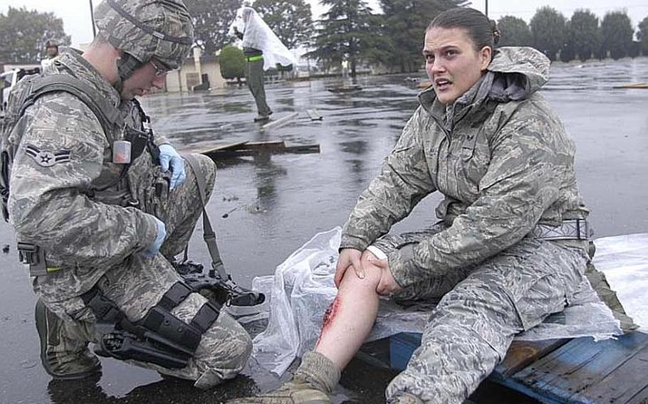 An airman first class from the 374th Security Forces Squadron comes to the aid of Senior Airman Amanda Kelly who grips her simulated injury -- a broken tibia -- during a mock disaster exercise on Nov. 6, 2012, at Yokota Air Base, Japan.