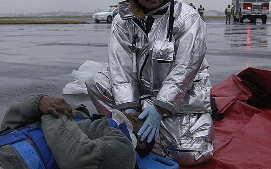 A Japanese firefighter from Yokota Air Base, Japan, stabilizes Senior Airman Anthony Washington during a mock disaster exercise at the base on Nov. 6, 2012. The scenario revolved around a tornado hitting the base.