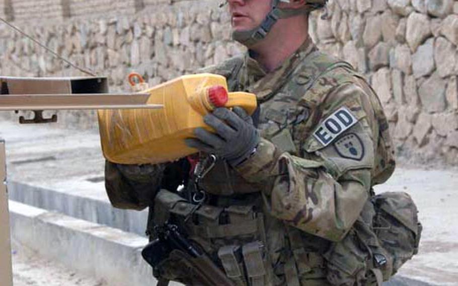 Sgt. B-Wesley Sanders, 25, of Corpus Christi, Texas, who is working with the 630th Ordnance Company out of Fort Riley, Kansas, retrieves a container of homemade explosive from a street in Qalat, Zabul Province, Afghanistan in September.