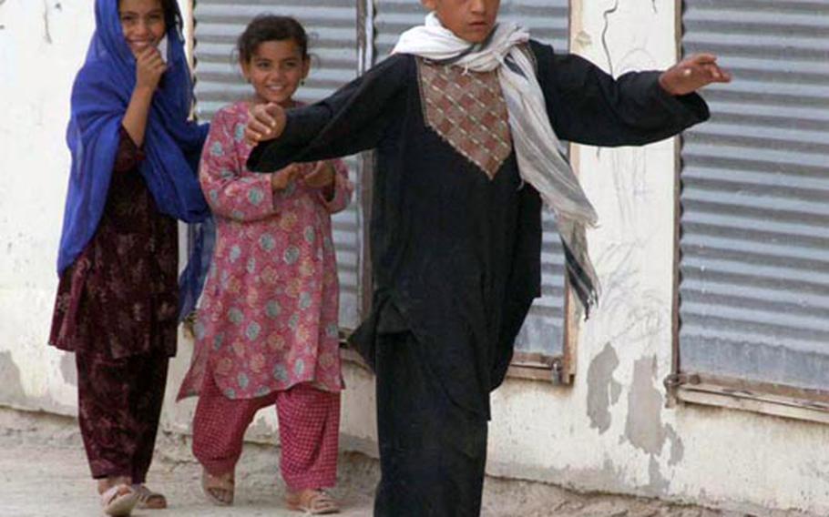 Afghan kids play in the street about 50 yards from a plastic container of explosive that U.S. Explosive Ordnance Disposal troops retrieved in Qalat, Zabul Province, Afghanistan in September. Despite billions of dollars in equipment and training, officials have been unable to lower the number of IED attacks.