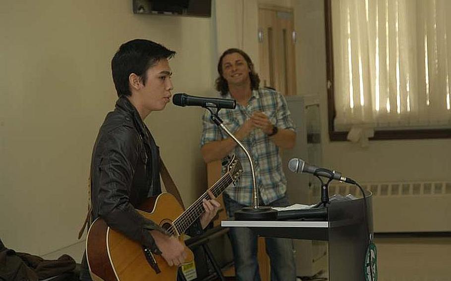 Singer-songwriter Wesley Cook, right, looks on as 16-year-old junior Patrick Waters performs for his fellow Daegu High School students on Camp Walker in South Korea on Thursday. Cook spoke and performed for students, and invited Waters to the microphone after finding out he is an aspiring musician.