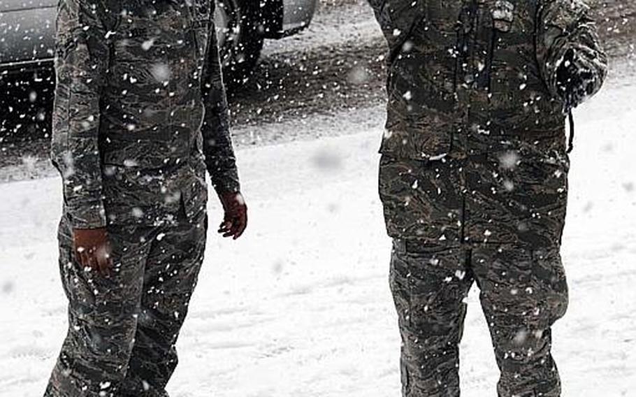 An airman enjoys the heavy snowfall as she tosses a snowball in the air at Osan Air Base, South Korea, during the first snowfall of the year in that area of the country.
