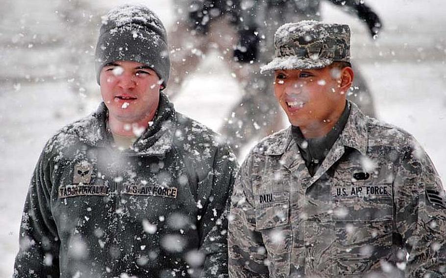 Two airmen walk down Songtan Boulevard as heavy snow falls Dec. 5, 2012, in South Korea. The snow led to the early closure of schools and various non-essential services across Osan Air Base.