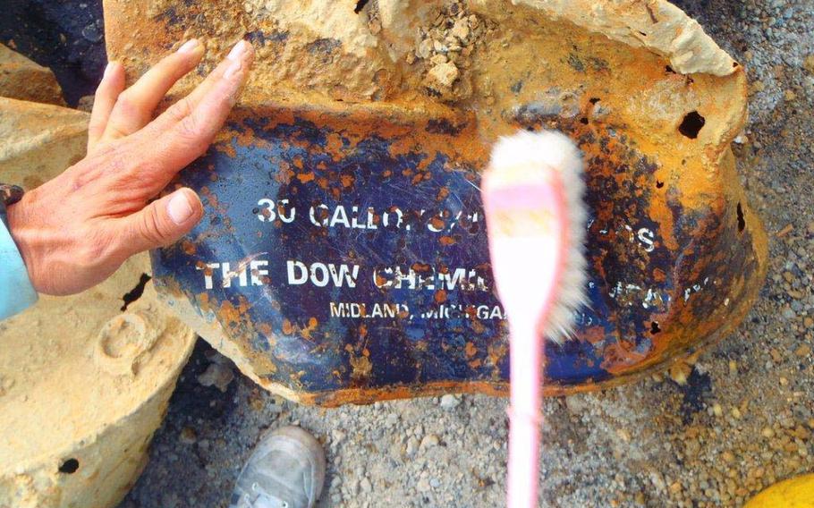 A Japanese worker brushes away dirt from one of 16 barrels unearthed in Okinawa City on June 13, 2013. The city called for Tokyo to investigate for Agent Orange, but manufacturer Dow Chemical Company denied the drums contained the herbicide.