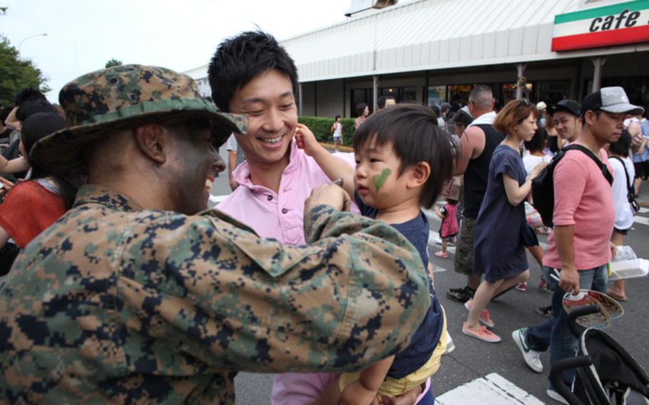 A Marine paints a Japanese boy's face with camouflage at the 37th annual Yokosuka Friendship Festival on Aug. 3, 2013. The Navy base was open to the Japanese public who were treated to live entertainment, food vendors and other events.