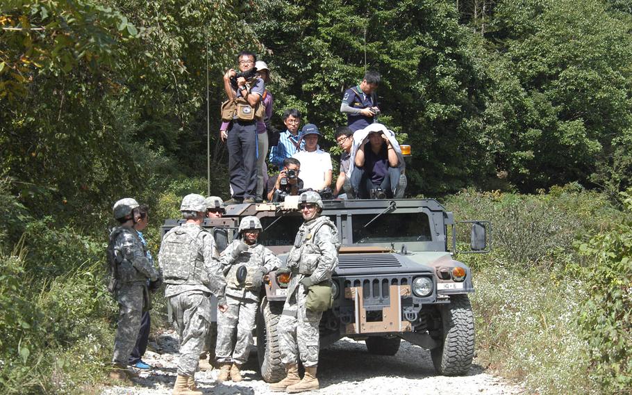 Korean media representatives look on as preparations are made for the firing of rockets during a U.S. military training exercise Sept. 25, 2013, near the Demilitarized Zone in South Korea. Crews from the 2nd Infantry Division's 6th Battalion, 37th Field Artillery Regiment, 210th Fires Brigade, were putting their Multiple Launch Rocket Systems through their their paces as part of the process they must go through every six months to maintain their certification.