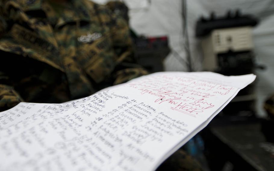 Navy Sr. Chief Vilma Rodriguez, a native of Tacloban, Philippines, holds a plea signed by nearly 200 people living in Tacloban requesting assistance and relief supplies in the wake of Super Typhoon Haiyan.