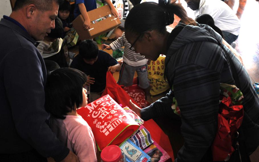 Lance Cpl. Jessica Nelson, right, a topographic analyst with 3rd Intelligence Battalion, helps children unwrap their gifts at the Nagomi Nursing Home for Children in Kin, Okinawa, Dec. 23, 2013. 

Lisa Tourtelot/Stars and Stripes