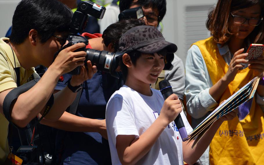 A Korean child speaks during a protest speaks during a protest across the street from the Japanese Embassy in Seoul, South Korea, on May 21, 2014. Members of the media close in to take photos of his speech during the protest of Japan forcing Korean women into prostitution during World War II.