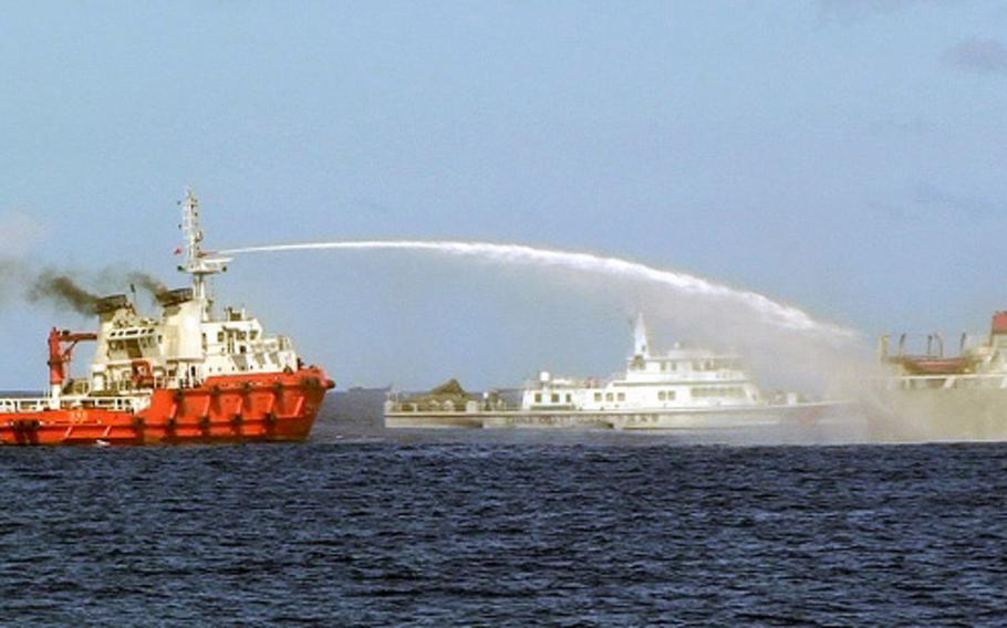 In this file image from Wednesday, May 7, 2014, a Chinese ship, left, shoots a water cannon at a Vietnamese vessel, right, while a Chinese coast guard ship, center, sails alongside in the South China Sea, off Vietnam's coast.