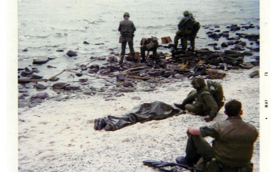 The body of Marine Lance Cpl. Ashton Loney lies on West Beach covered in a poncho after he was killed in action during the battle of Koh Tang. This photograph was taken by Marine Fred Morris during a lull in the fighting. Loney remains unaccounted for after his body was left behind during the confusion of the evacuation and fighting.