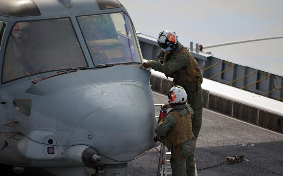 Crewmen of a Marine MV-22 Osprey perform a quick check on the aircraft's windshield on March 26, 2015. The MV-22 was 1 of 2 Osprey aircraft performing touch-and-go landings aboard the South Korean vessel ROKS Dokdo. 

