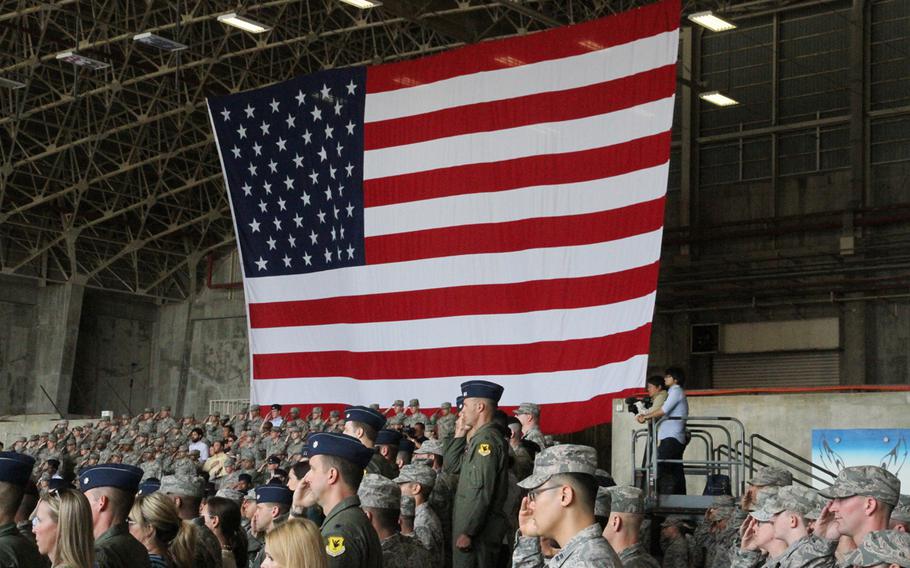 Airmen salute during the playing of the national anthem before the 18th Wing change-of-command ceremony Thursday, April 2, 2015, at Kadena Air Base, Okinawa. Brig. Gen. James Hecker was replaced by Brig. Gen. Barry Cornish as commander.