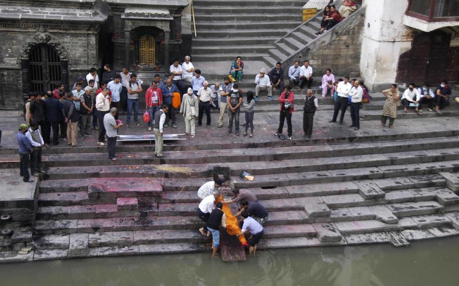 Family members wash the body of a deceased relative in the Bagmati River, Nepal. Afterward, the body will be carried to a pyre and cremated.