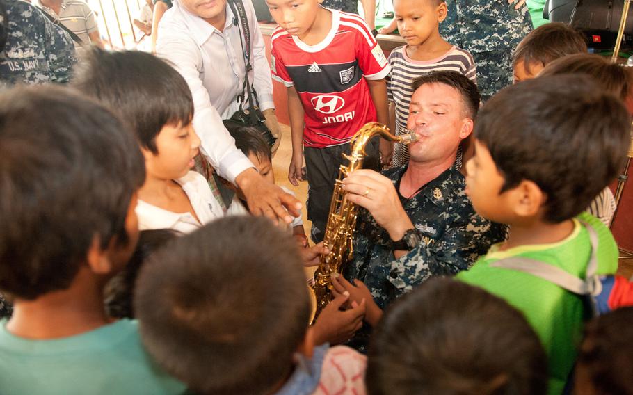 Children attending M'Lop Tapang school in Sihanoukville, Cambodia, gather around Chief Petty Officer Gresh Laing, with the Pacific Fleet Band, during a Pacific Partnership community service event in 2014. The Fleet Band is one of the Navy's primary means of fostering goodwill among citizens of nations in the Pacific.