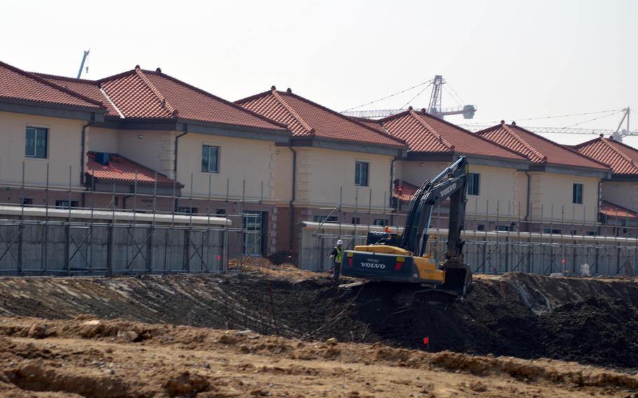 A South Korean construction worker guides an excavator at a construction site at Camp Humphreys, South Korea, on April 24, 2015. Behind the wall is a row of field grade officer housing.