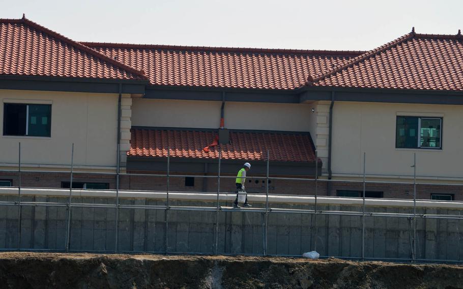 A South Korean construction worker walks alongside a wall at Camp Humphreys, South Korea, on April 24, 2015. Behind the wall is a row of field grade officer housing.