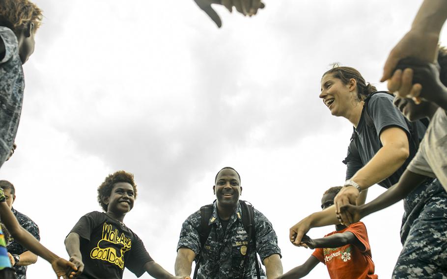 Command Master Chief Dedrick Walker, attached to the Military Sealift Command hospital ship USNS Mercy, dances with children during Pacific Partnership, June 28, 2015. Mercy was in Papua New Guinea for its second mission port of Pacific Partnership. 

Mark El-Rayes/U.S. Navy