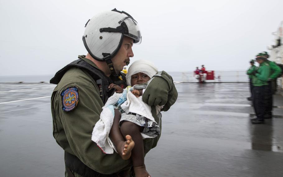 Hospital Corpsman 1st Class Matthew Hawkins, assigned to Helicopter Sea Combat Squadron 21, assists an infant aboard the Military Sealift Command hospital ship USNS Mercy June 30, 2015. Mercy launched one of its helicopters to transport six passengers, including one infant, who swam ashore after their ship sank off the coast of Carteret Island in Papua New Guinea.  Mercy was in Papua New Guinea as part of Pacific Partnership 2015.