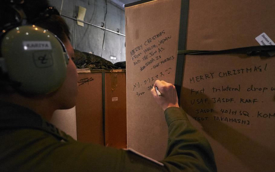 A Japan Air Self-Defense Force airman writes a Christmas message to people living on the island of Luknor in Micronesia on Wednesday, Dec. 9, 2015.  