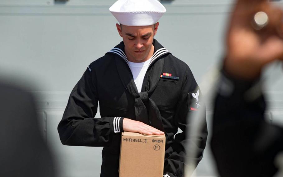 Gunner's Mate 3rd Class Robert Ashman carries the remains of his Navy veteran great-grandfather during a burial-at-sea ceremony aboard the USS Winston S. Churchill in the Mediterranean Sea, April 23, 2018.