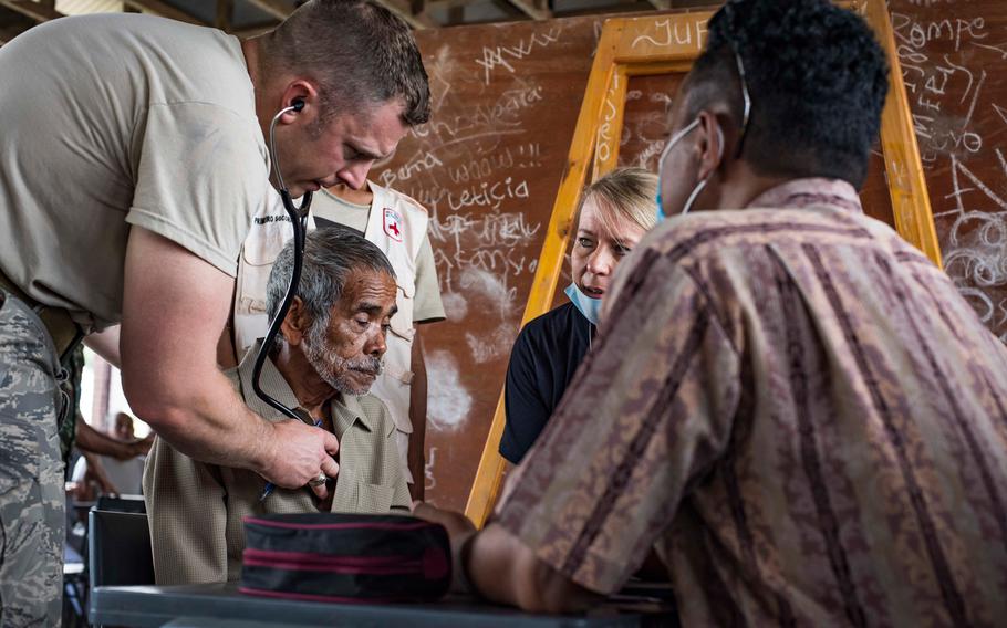 Airmen examine a patient while Marcelino Piedade, right, a translator from Dili, Timor-Leste, translates for the medical staff at the Negri Saran Kote Secondary School during Pacific Angel 2018 in Suai, Cova Lima Municipality, Southwest Timor-Leste, June 11, 2018.