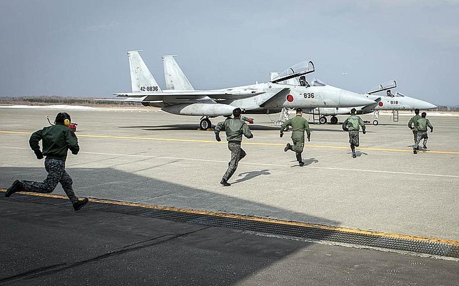 Japanese pilots race to two F-15J Eagles during a scramble demonstration last year at Chitose Air Base, Japan.