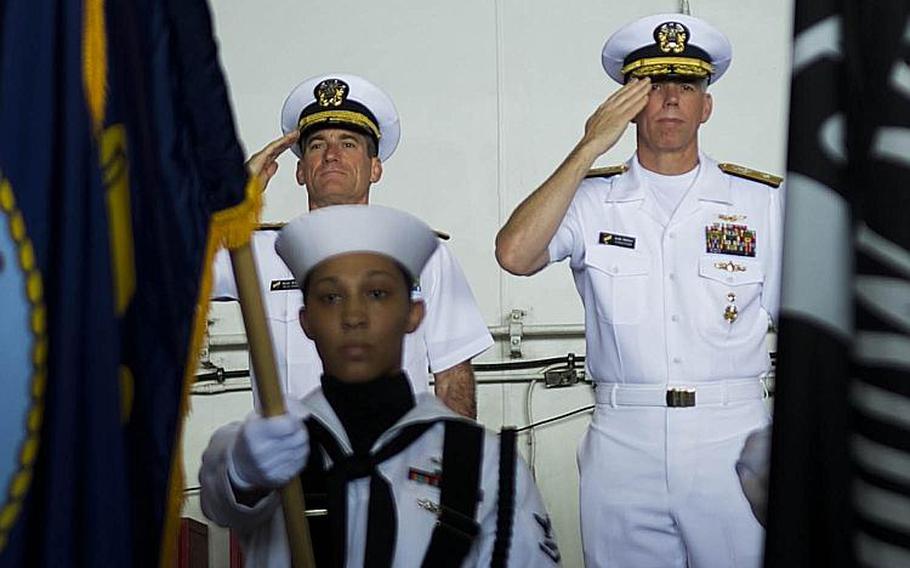 Rear Adm. Marc Dalton, left, and Rear Adm. Karl Thomas salute the colors during the Task Force 70 change-of-command ceremony aboard the USS Ronald Reagan in the Philippine Sea, Wednesday, July 18, 2018.