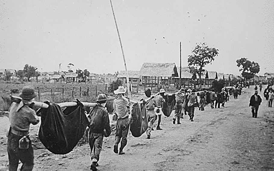 American and Filipino prisoners of war carry dead comrades after the Bataan Death March in May 1942.