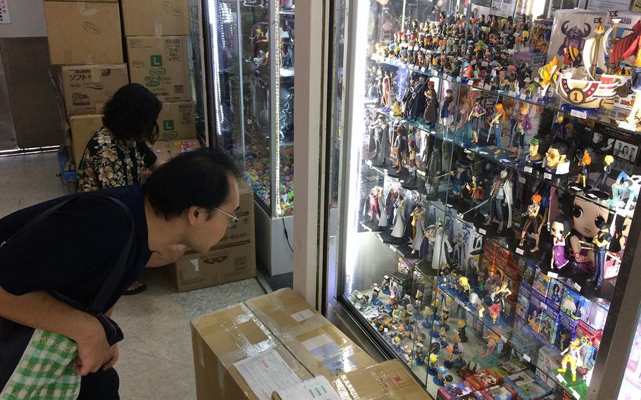 A customer gets a closer look at a display case featuring only a small sample of the many cases on display selling anime figurines at Nakano Broadway in Tokyo.