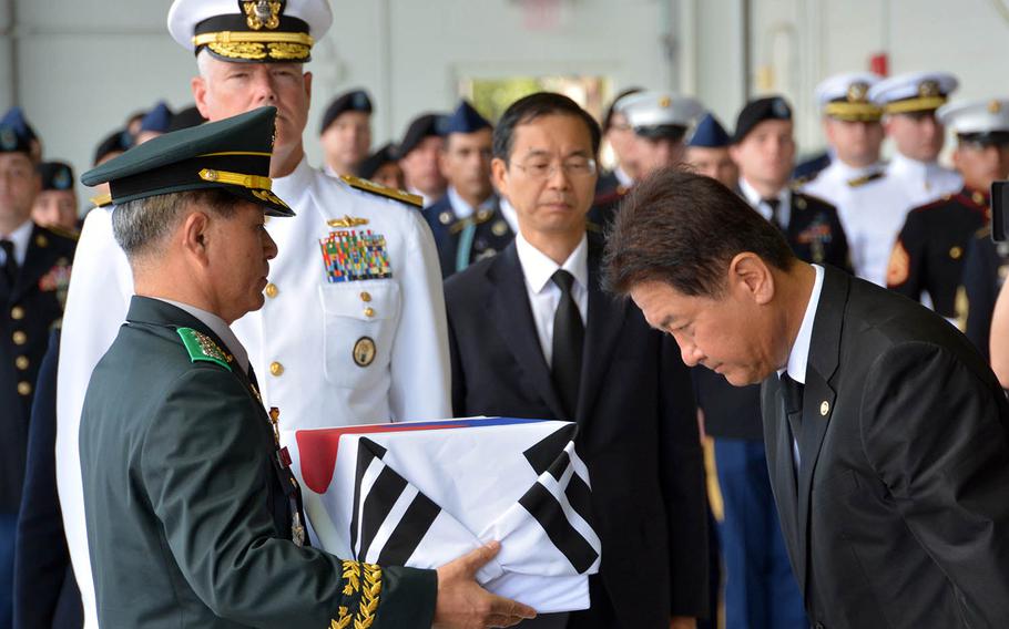 South Korean Vice Minister of National Defense Choo Suk Suh bows as he transfers a box of remains to Col. Hak Ki Lee, commander of the KIA Recovery and Identification agency, during a repatriation ceremony at Joint Base Pearl Harbor-Hickam, Hawaii, Thursday, Sept. 27, 2018.