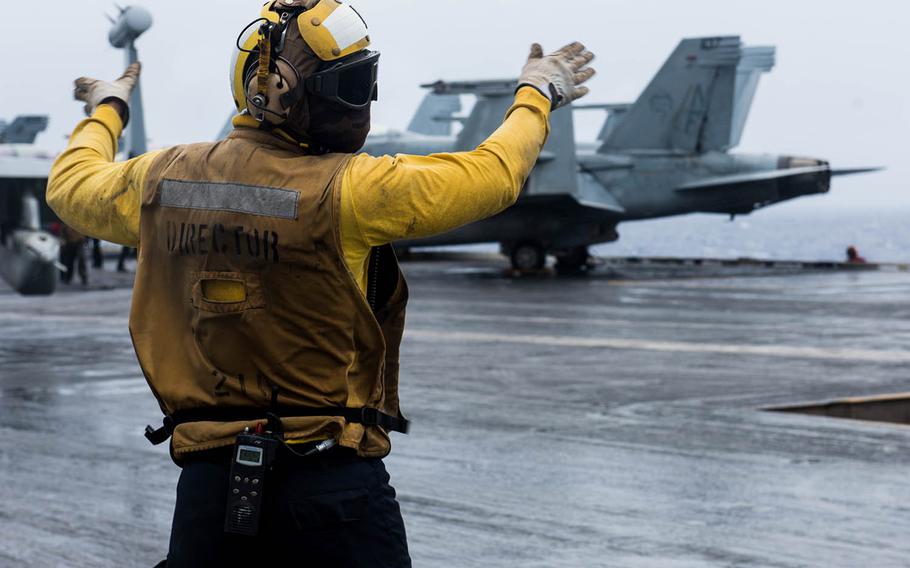 An aviation boatswain's mate directs an aircraft on the flight deck of the aircraft carrier USS Ronald Reagan in the Philippine Sea, Sept. 20, 2018.