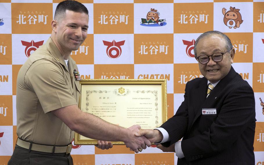 Marine Maj. William Easter, left, of the III Marine Expeditionary Force on Okinawa, receives a letter of appreciation Tuesday, Jan. 22, 2019, from Chatan Mayor Masaharu Noguni for a rescue at sea in December.