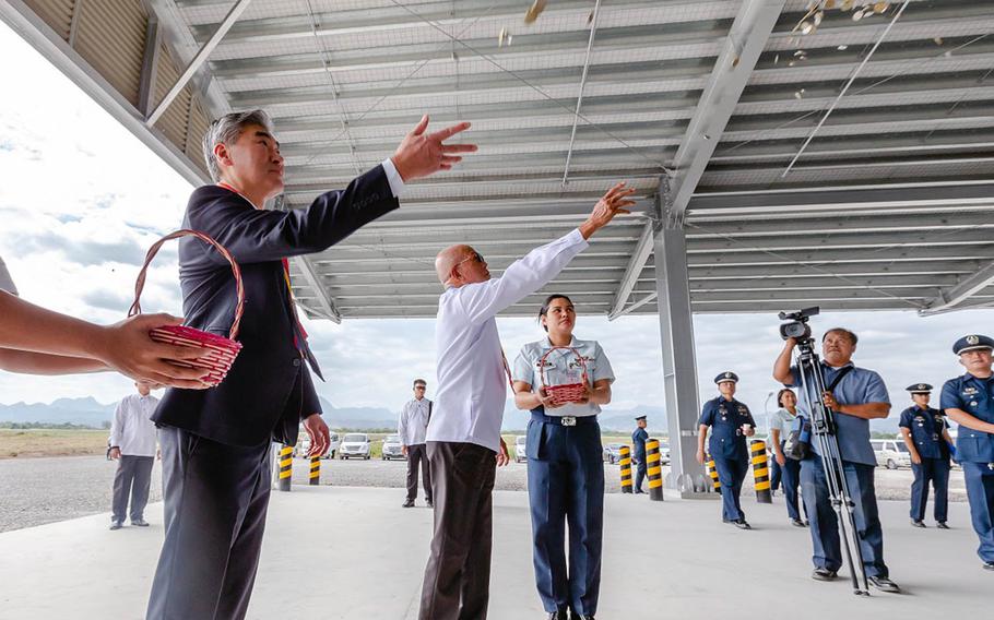 U.S. Ambassador Sung Y. Kim and Philippine Defense Secretary Dlfin Lorenzana toss coins Tuesday, Jan. 29, 2019, at the Basa Air Base Humanitarian Assistance and Disaster Relief warehouse, symbolizing good fortune for the new building.