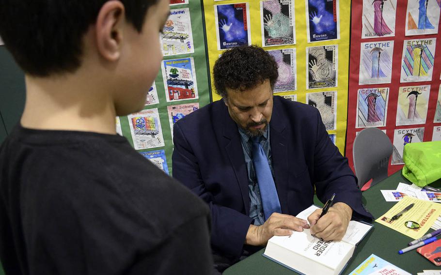 Bestselling author Neal Shusterman signs a copy of one of his books for a sixth-grader during Shusterman's visit to Yokosuka Middle School, Japan, Thursday, Jan. 31, 2019.