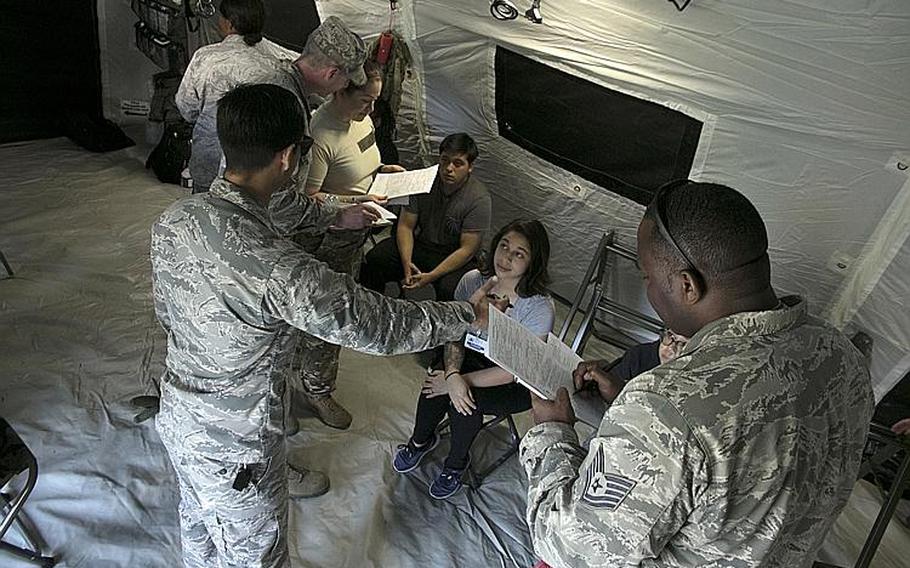 Air Force Capt. Michael Strong, left foreground, and Tech Sgt. Damian Sharpe, right foreground, in-process simulated casualties inside a pop-up En-Route Patient Staging System and prepare them for travel during an exercise at Kadena Air Base, Okinawa, Wednesday, March 27, 2019.