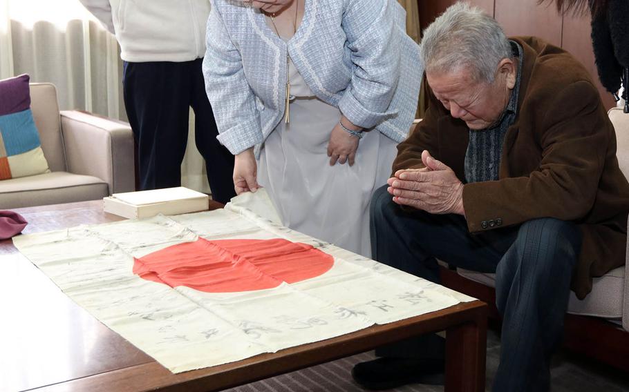 Jitsuo Matsue prays over a flag carried by his father, Hisao Matsue, during World War II, after it was returned to his family at the town hall in Kamigori, Japan, March 17, 2019.