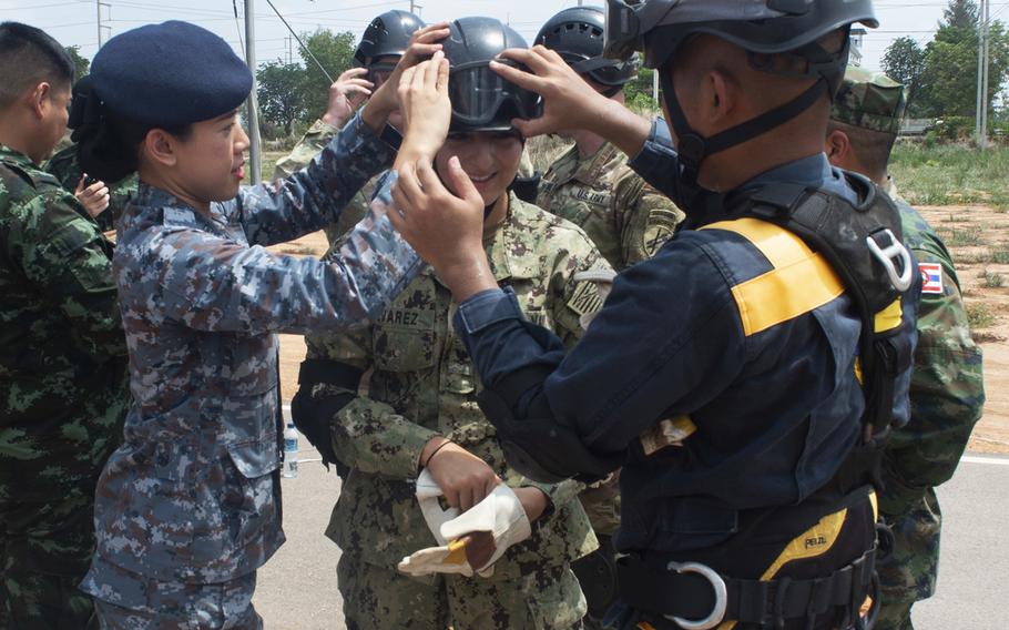 Members of the Thai Royal Armed Forces assist Petty Officer 3rd Class Sandra Alvarez, assigned to Pacific Partnership 2019, with her protective gear during a humanitarian-assistance and disaster-relief demonstration in Chachoengsao province, Thailand, May 23, 2019.