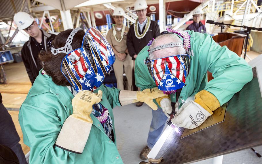 Irene Hirano Inouye, left, and Frank Wood, a Bath Iron Works welder, authenticate the keel of the future guided-missile destroyer USS Daniel Inouye at Bath Iron Works, Maine, May 14, 2018.