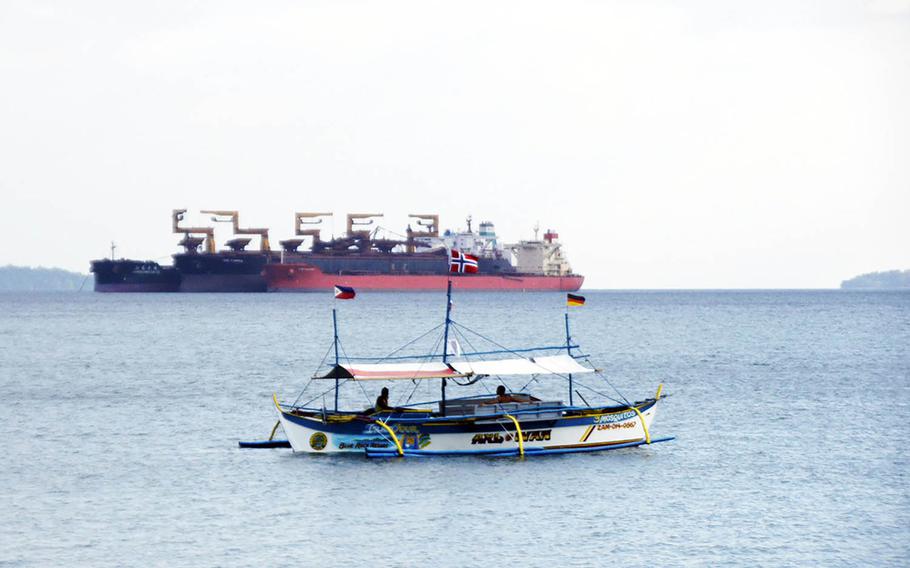 A tourist boat drifts in front of a commercial vessel near Baloy Beach in Subic Bay, Philippines, in March 2015.