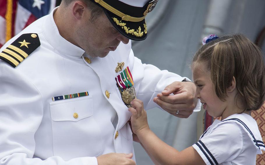 Cmdr. Micah Murphy’s daughter helps her father during a change-of-command ceremony for the USS John S. McCain at Yokosuka Naval Base, Japan, Tuesday, July 2, 2019.